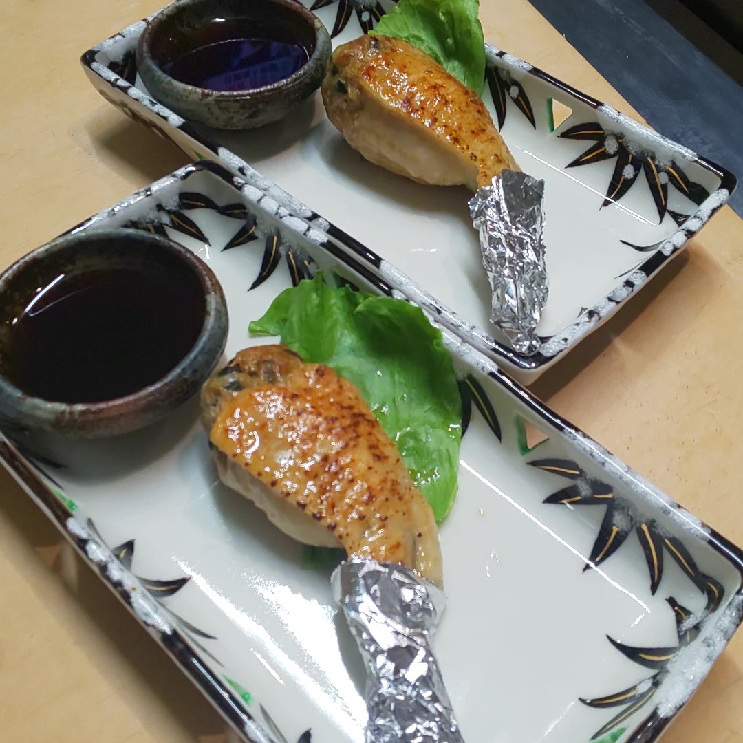 皿に盛られた手羽ギョーザ。タレの小鉢とレタスが添えられている