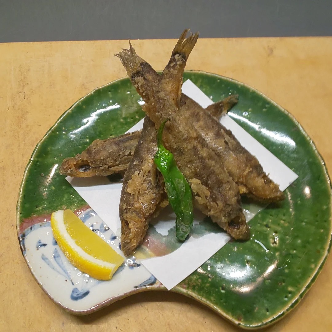 メヒカリの唐揚げ。レモンとししとうが添えられている