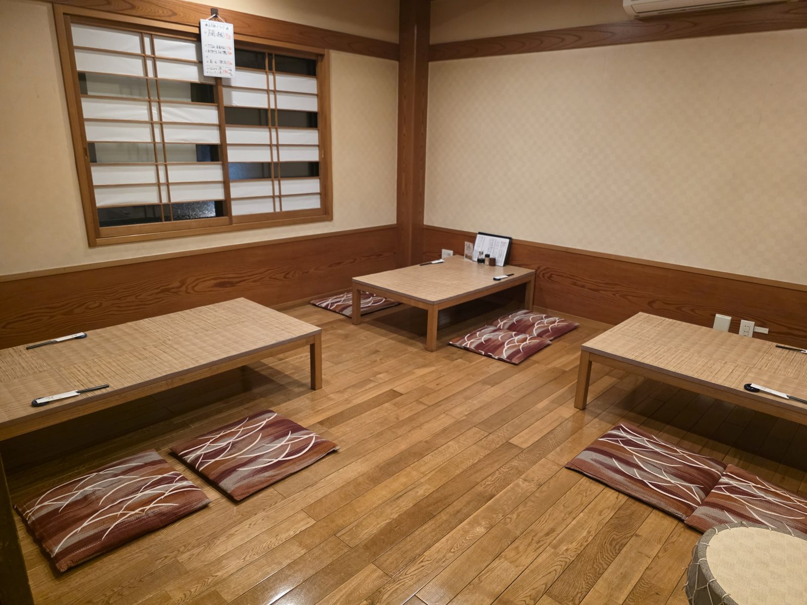 窓のある座敷。テーブル3卓と座布団