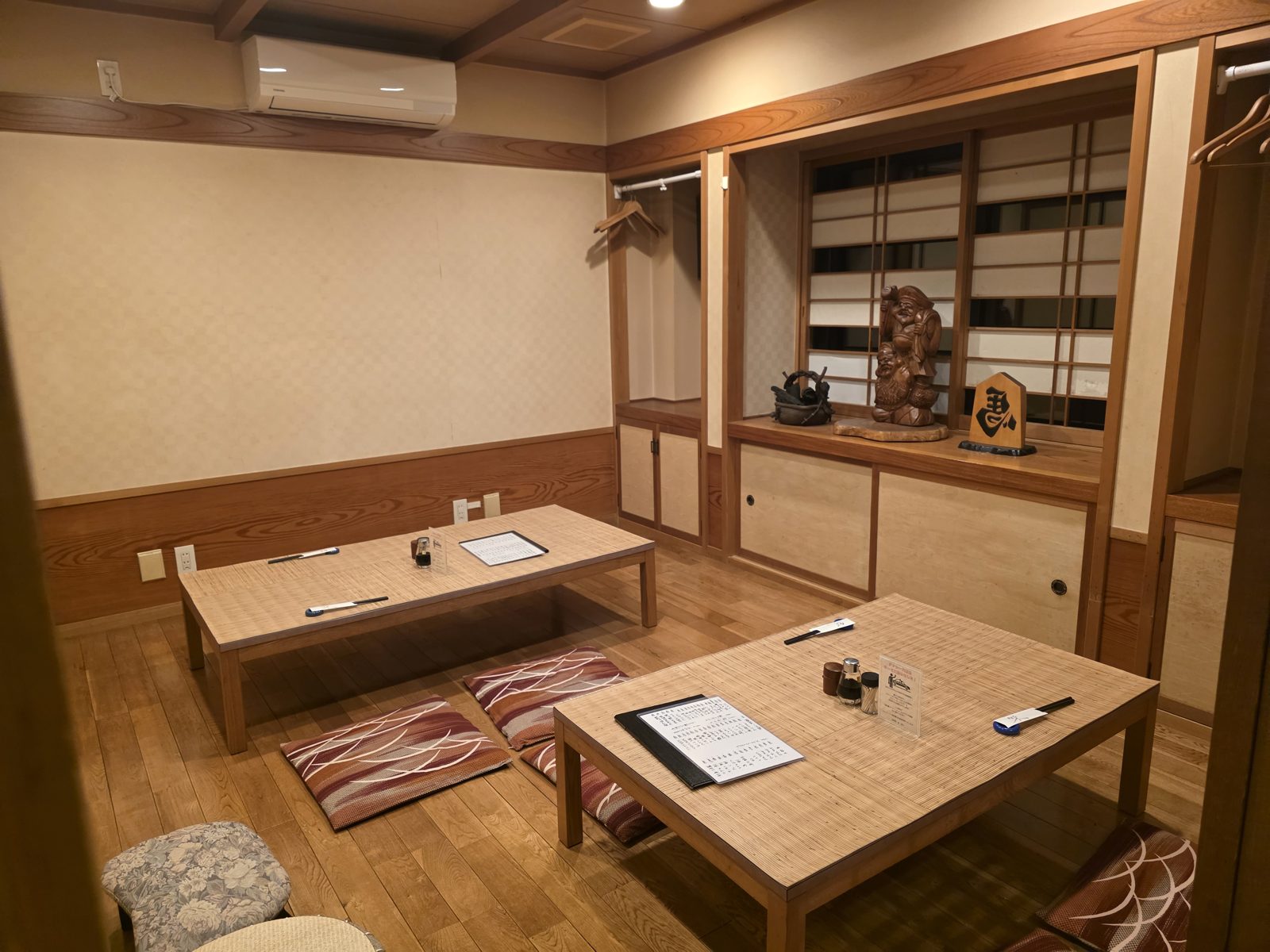 恵比寿様の木彫りが飾られた座敷。テーブル2卓とハンガー掛け
