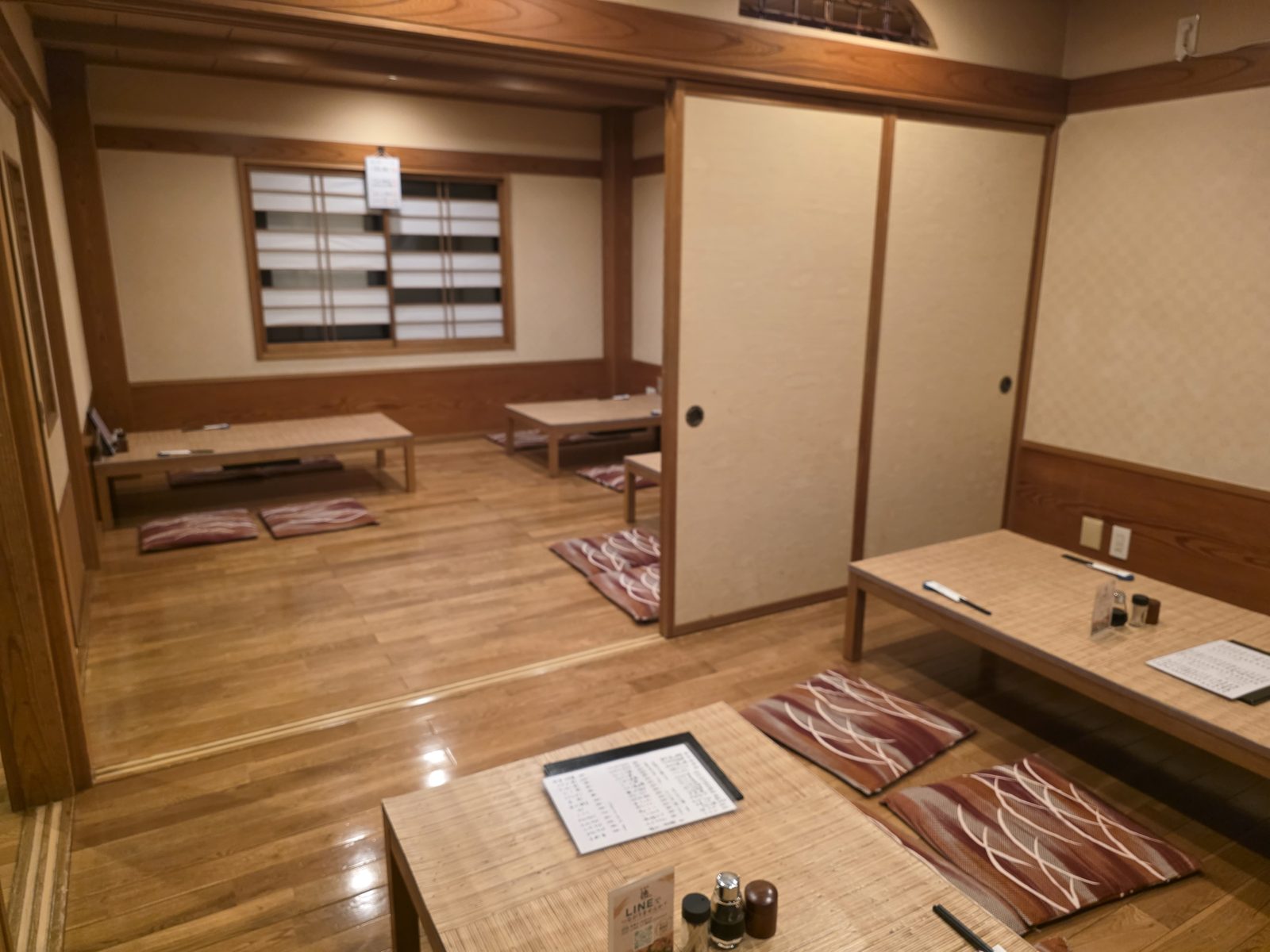 襖を開けて二間がつながった座敷。低いテーブルと座布団が並ぶ